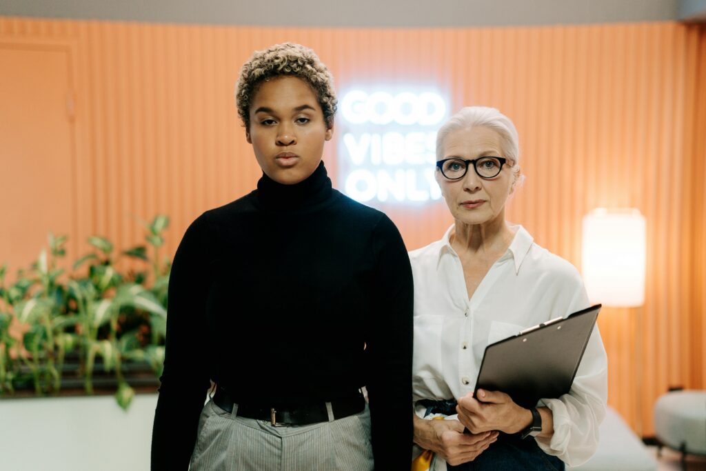 Two diverse women standing together in a contemporary office environment with professional attire.